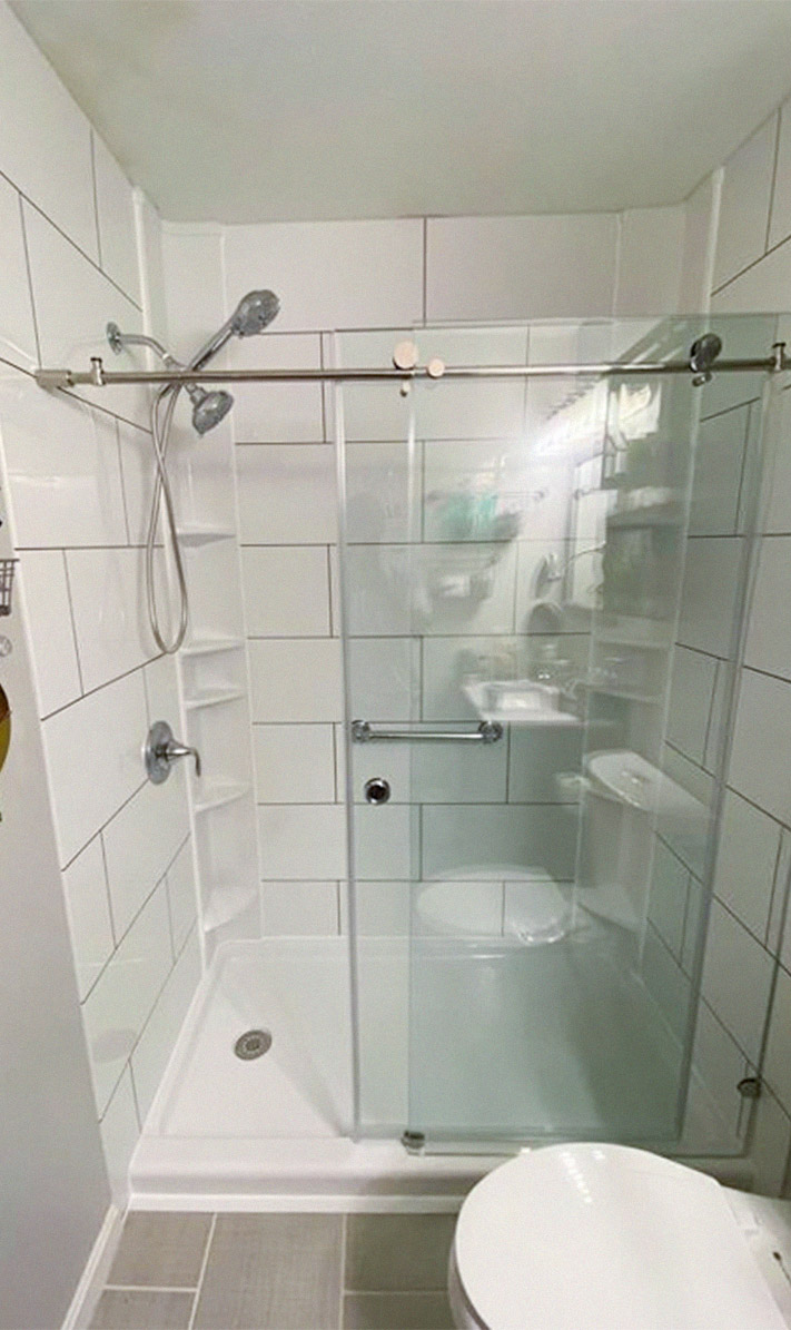pristine white-tiled shower with new glass sliding door